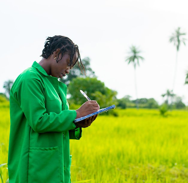 Female farmer taking notes in a green field